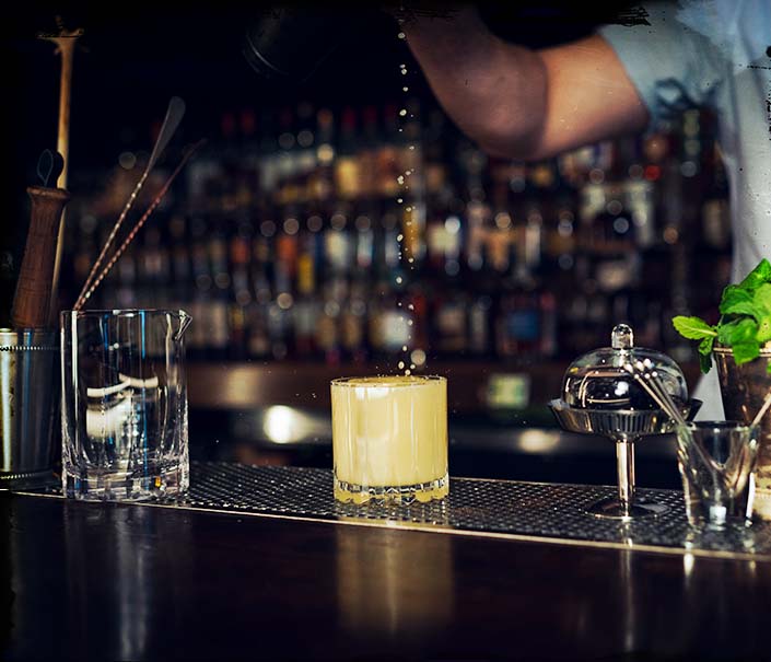 Bartender making Orangano whiskey cocktail in rocks glass with shaker strainer - Redemption Whiskey